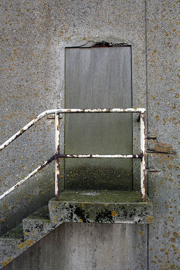 Photo 00377: No door. Decayed door blocked with unpainted plywood board.