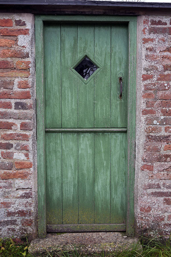 Photo 09807: Worn, green half-door made of planks with a diamond-shaped door light