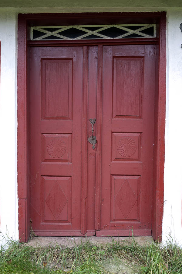 Photo 09831: Lopsided, carved, panelled, red and white double door with top window