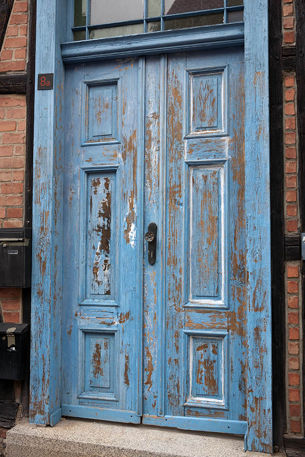 Photo 12733: Worn, panelled, blue double door with top window under repair