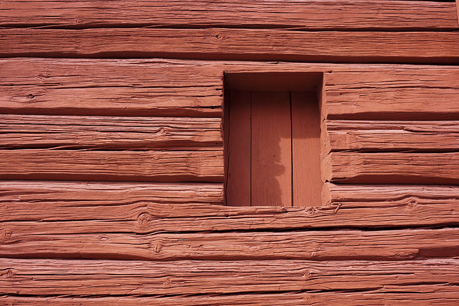 Photo 18188: No window. A hole in a red loghouse barred by boards