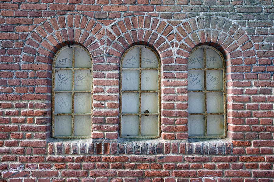Photo 25287: Facade with three worn, formed, white metal windows in a red brick wall