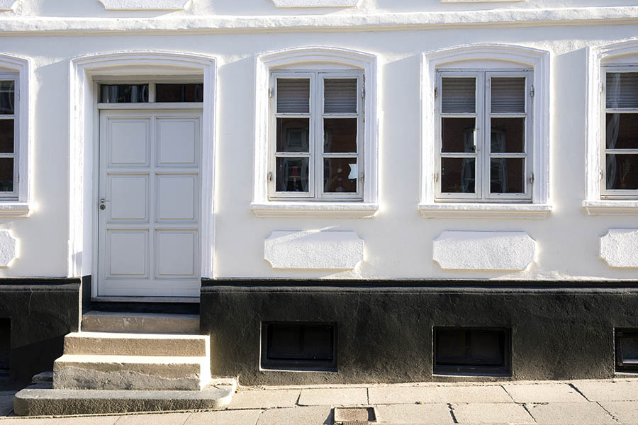 Photo 25298: Facade with panelled, grey door and three grey windows in a plastered, white wall