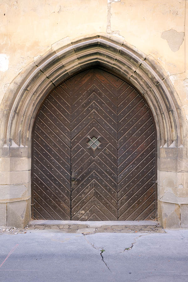 Photo 25353: Formed, brown church gate  with diagonal boards, many nails, and a barred door light