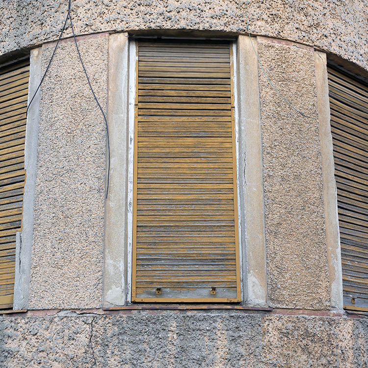 Photo 25582: Facade with three worn, yellow, wooden security shutters