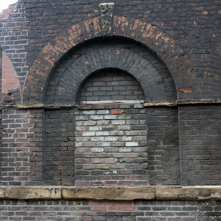 Photo 11618: Worn, red and black brick wall with half-circle indentations