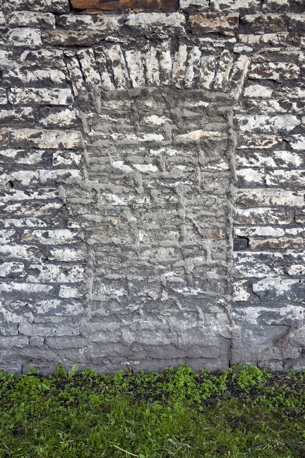 Photo 19850: Worn, grey and white brick wall with remains of a window