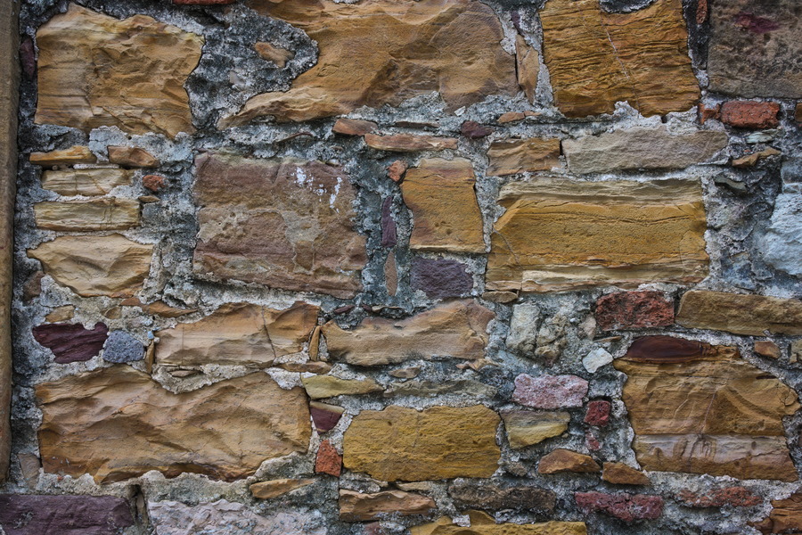 Photo 27442: Worn stone wall with red, yellow and brown stones.