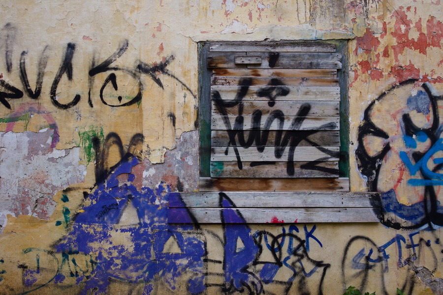 Photo 27464: Decayed, plastered, yellow wall with blocked window and grafitti