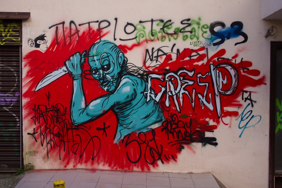 Photo 27469: Plastered, light yellow wall with large grafitti: Blue man with knife