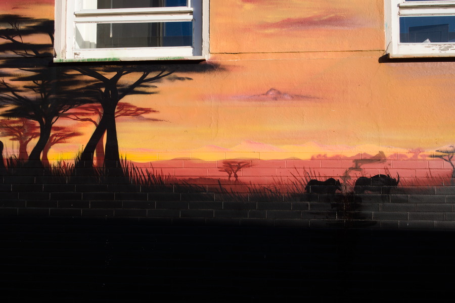 Photo 27487: Orange, plastered wall with grafitti: African landscape in yellow, orange and black