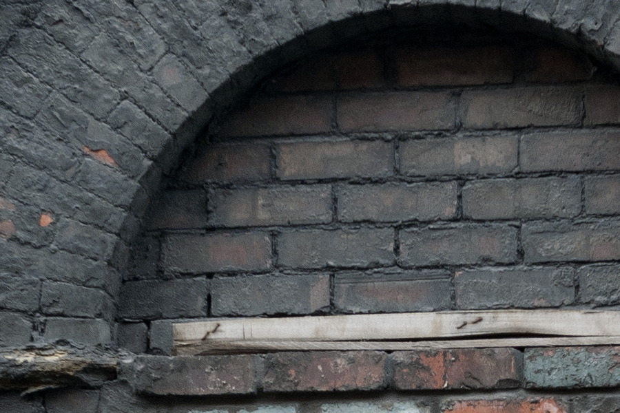 Photo 11618: Worn, red and black brick wall with half-circle indentations