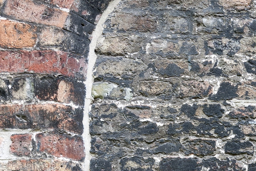 Photo 15908: Worn wall of black, yellow and red bricks with indentation