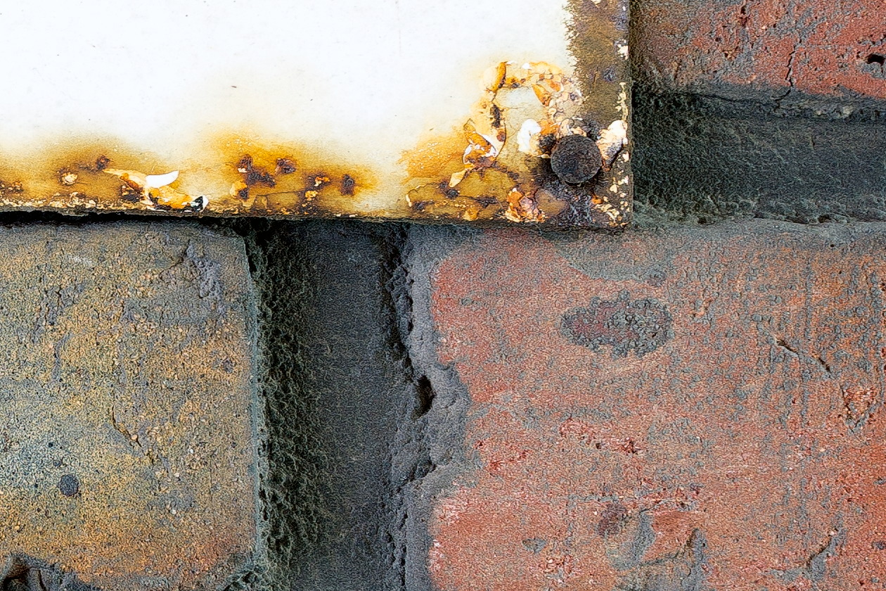 Photo 25222: Worn, red brick wall with rusty sign 