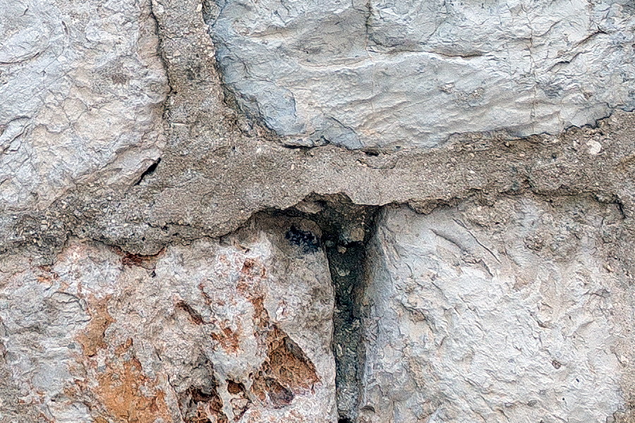 Photo 26268: Worn, grey stone wall with a window frame blocked by more stones