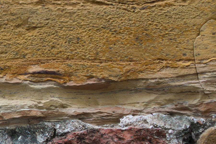 Photo 27442: Worn stone wall with red, yellow and brown stones.